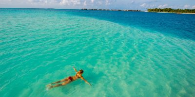 Maldives, Rangali Island. Conrad Hilton Resort. Woman swimming in the Indian ocean. (MR)