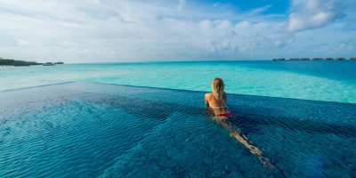 Maldives, Rangali Island. Conrad Hilton Resort. Woman in an infinity pool on the ocean. (MR)